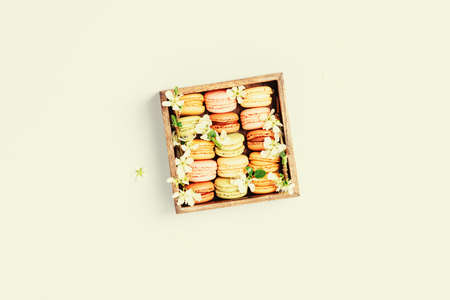 Macaroons in wooden box with spring flowers flat layの写真素材