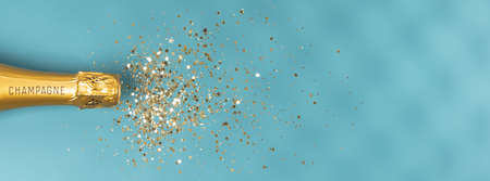 Bottle of champagne and confetti on pink background, top view.の写真素材