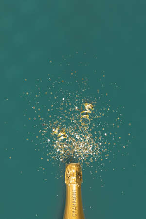 Bottle of champagne and confetti on green background, top view.の写真素材