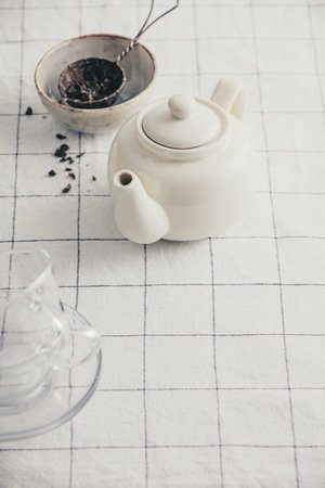 White teapot, cups and strainer on the checkered table clothの写真素材