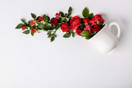 Creative layout made of coffee or tea cup with red roses on white backgroundの写真素材