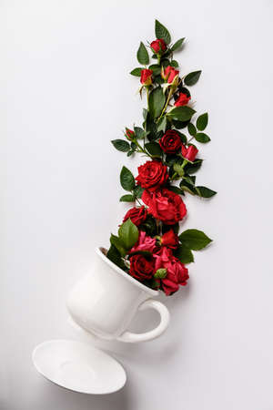 Creative layout made of coffee or tea cup with red roses on white backgroundの写真素材