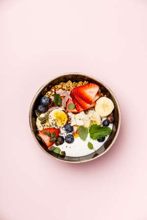 Oat granola with fresh berries, banana, yogurt, maple syrup, seeds and mint leavesの写真素材