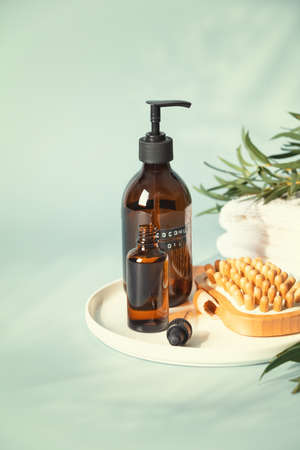 Amber glass bottles with wooden massage brush, eucalyptus leaves and towels. Eco friendly massage and body care conceptの写真素材