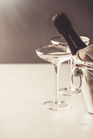 Champagne bottle in bucket and glasses on concrete backgroundの写真素材