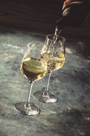 White wine pouring into glasses, close upの写真素材