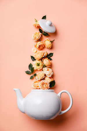 Creative layout made of whte tea pot with orange roses on pink backgroundの写真素材