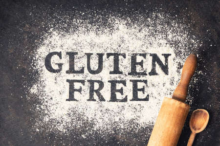 Gluten free written in flour, rolling pin and old spoon on vintage baking sheetの写真素材