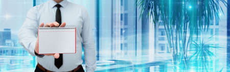 Man Wearing Black Tie Holding Empty Page Graphing Notebook Around Futuristic Technology. Employee Presenting Blank Workbook Surrounded By Modern Automation.の写真素材