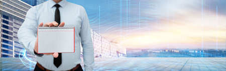 Man Wearing Black Tie Holding Empty Page Graphing Notebook Around Futuristic Technology. Employee Presenting Blank Workbook Surrounded By Modern Automation.の写真素材