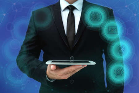 Man In Office Uniform Standing Holding Tablet Displaying New Modern Technology. Gentleman In Business Attire Carrying Tab Pointing New Futuristic Technology.の写真素材