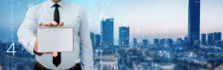 Man Wearing Black Tie Holding Empty Page Graphing Notebook Around Futuristic Technology. Employee Presenting Blank Workbook Surrounded By Modern Automation.の写真素材