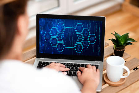 Woman Typing On Laptop Beside Coffe Mug And Beautiful Plant Accomplishing Work From Home. Girl Encoding Minicomputer Next To Cap And Flower Finishing Remote Jobs.の写真素材