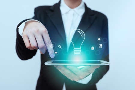 Lady In Suit Standing Pointing On Tablet Showing Futuristic Graphic Interface. Woman In Uniform Holding Mobile Device Presenting Modern Virtual Technologies.の写真素材