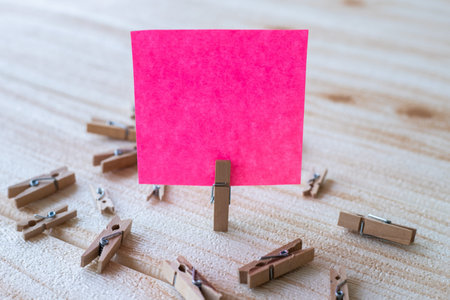 Piece Of Blank Square Note Surrounded By Laundry Clips Showing New Meaning. Empty Sticky Paper Clipped Upright Placed On Top Of Wooden Table Displaying Fresh Idea.の写真素材