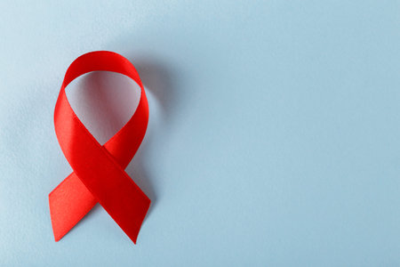 Red ribbon on blue background space for text World Cancer Day