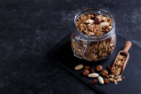 Homemade healthy granola made of oats nuts and fruits on black stone background copy spaceの写真素材