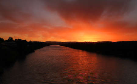 Red sky sunset over river with distant mountainsの写真素材