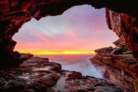 Coastal cave views to glorious sunrise over the oceanの写真素材