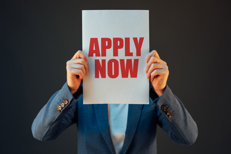Business woman holding paper with Apply Now message printed in red color - concept of new job application, employment and career opportunitiesの写真素材