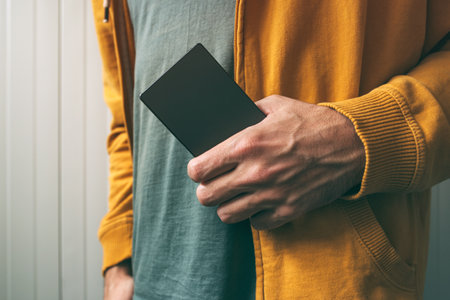 Casual young man posing with mobile phone in hand, technology and lifestyle conceptの写真素材