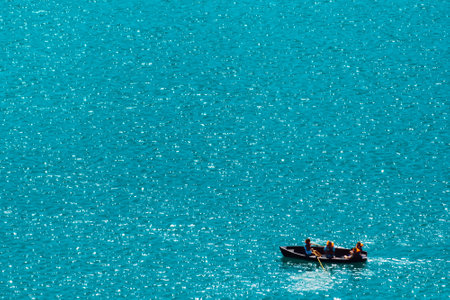 Unrecognizable people rowing in boat on lake, vast water surface as copy spaceの写真素材