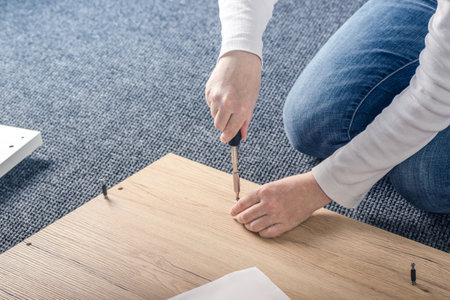 Woman assembling furniture at home on the floor, hand with screwdriverの写真素材
