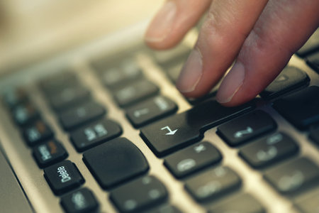 Finger pressing Enter key on laptop computer keyboard, close up, selective focus