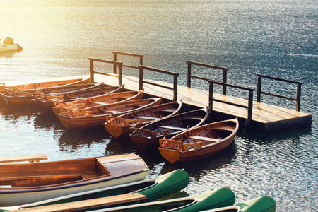 Small wooden boats and canoes docked and tied to empty pier on the lakeの写真素材