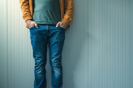 Tall unrecognizable casual man in jeans posing, wall as copy spaceの写真素材
