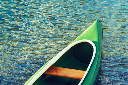Green plastic canoe on lake in summer afternoon