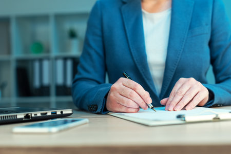 Female executive approves corporate business plan and signing document on office deskの写真素材