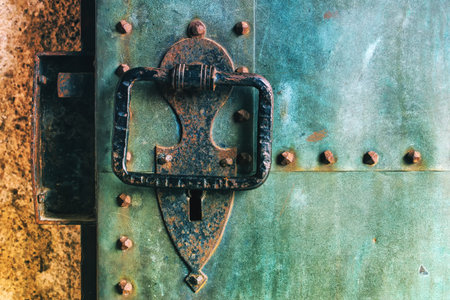 Old rustic copper metal castle door with large knocker, weathered surface texture