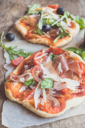 Prosciutto mini pizza with parmesan cheese on wooden background