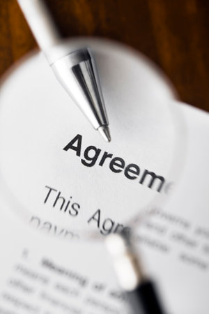 Magnifying glass over agreement paperwork and penの写真素材