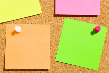 bulletin board and multi colored stickies attached with push pins. Copy spaceの写真素材