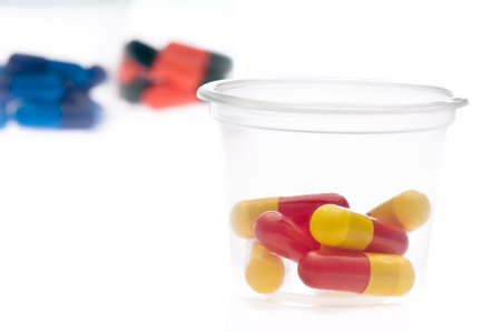 Colorful tablets, capsules in a container, over whiteの写真素材