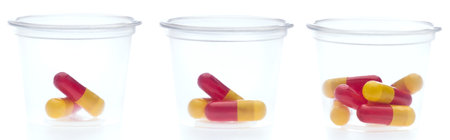 Three containers with different amount of pills, over whiteの写真素材