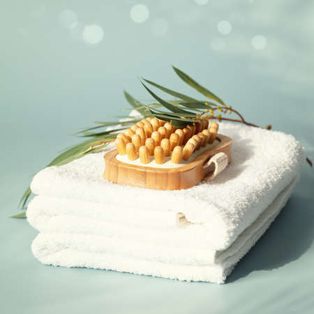 Massage wooden brush on white spa towels with eucalyptus leaves pastel blue background, anti-cellulite massage and body care conceptの写真素材