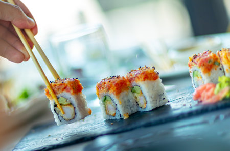 A man in an asian restaurant, eating sushi with chopsticks, trendy oriental food, traditional Japanese cuisineの写真素材