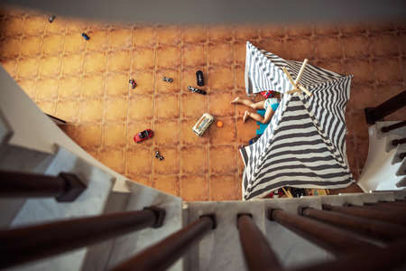 Baby boy playing at home, lying down in his tent, top view from up, little playful kid, happy carefree childhoodの写真素材