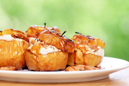 Closeup photo of a tasty baked apples stuffed with cream honey and nuts, healthy nutrition, delicious sweet food, gorgeous fruit dessert flavored with cinnamonの写真素材
