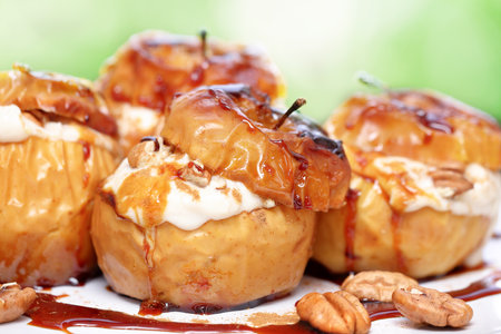 Closeup photo of a tasty baked apples stuffed with cream honey and nuts, healthy nutrition, delicious sweet food, gorgeous fruit dessert flavored with cinnamon..の写真素材
