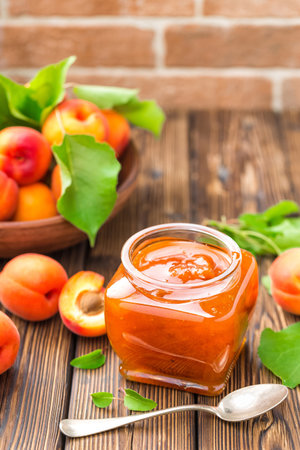 Apricot jam in a jar and fresh fruits with leavesの写真素材