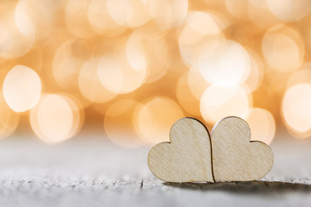 Two handmade wooden hearts on beautiful golden bokeh background. Vintage style. Love Valentine's Day concept.の写真素材