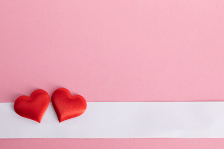 Valentine's day two red silk hearts and white paper on pink paper background, love conceptの写真素材