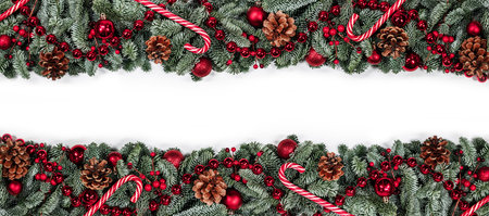 Christmas border frame design copmosition of noble fir tree branch and red decorations balls baubles berries pine cones isolated on white backgroundの写真素材