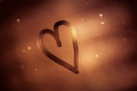 Love is in the air, heart shaped drawing on the misted-up window, abstract golden brown background, romantic winter holidays concept, happy Valentines day..の写真素材