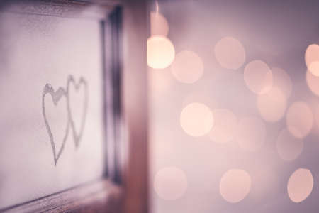 Open doors to love, two hand drawn hearts on the open door, festive blurry bokeh lights background, romantic winter holiday, conceptual photo of first affection or true love, Valentines day holidayの写真素材