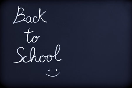 Back to school background, conceptual phrase with drawing of a smiley face on the blackboard, beginning of educational seasonの写真素材